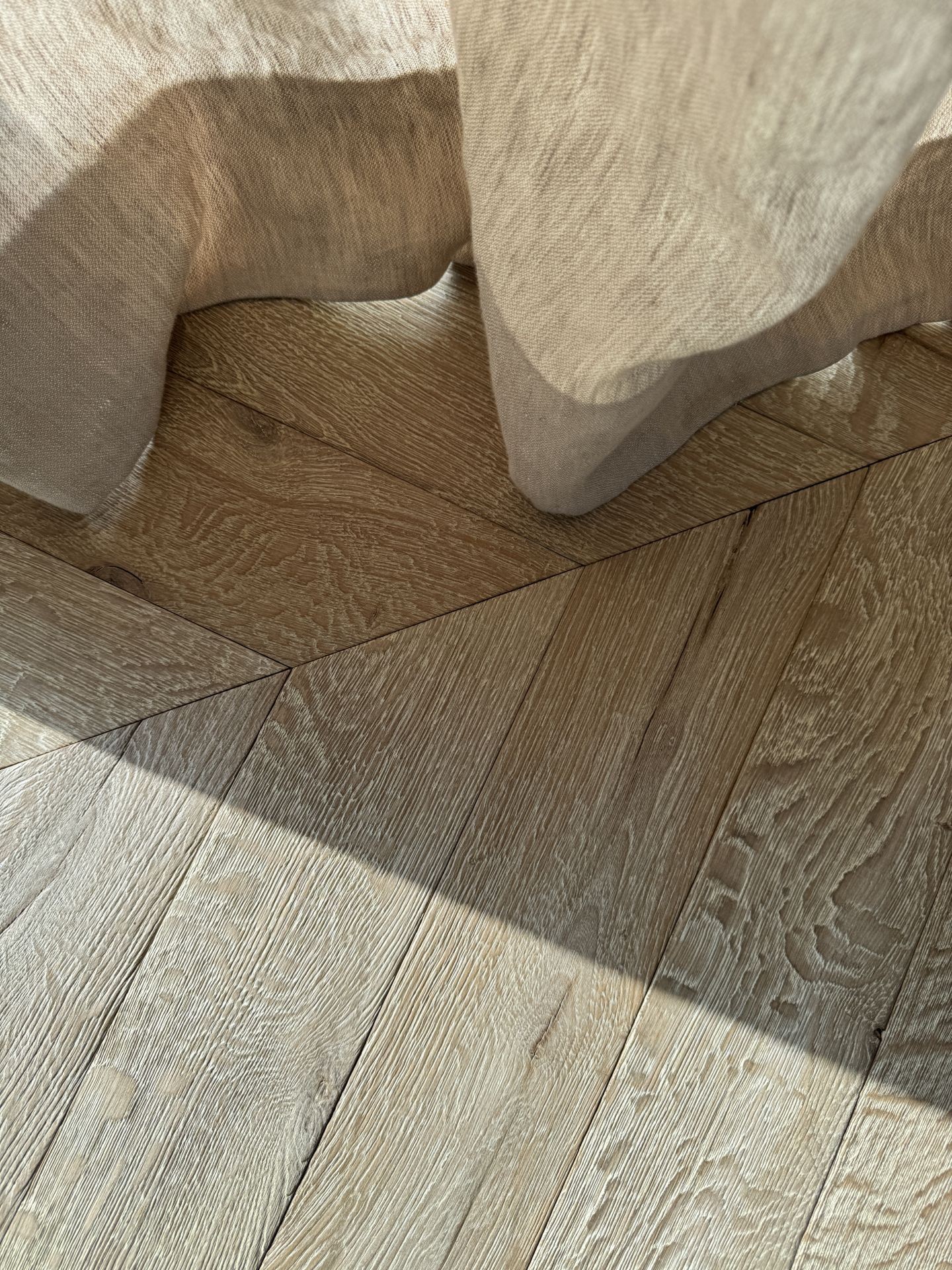 Chevron and wide plank oak flooring meeting under a linen cloth, VOGUE Parquet